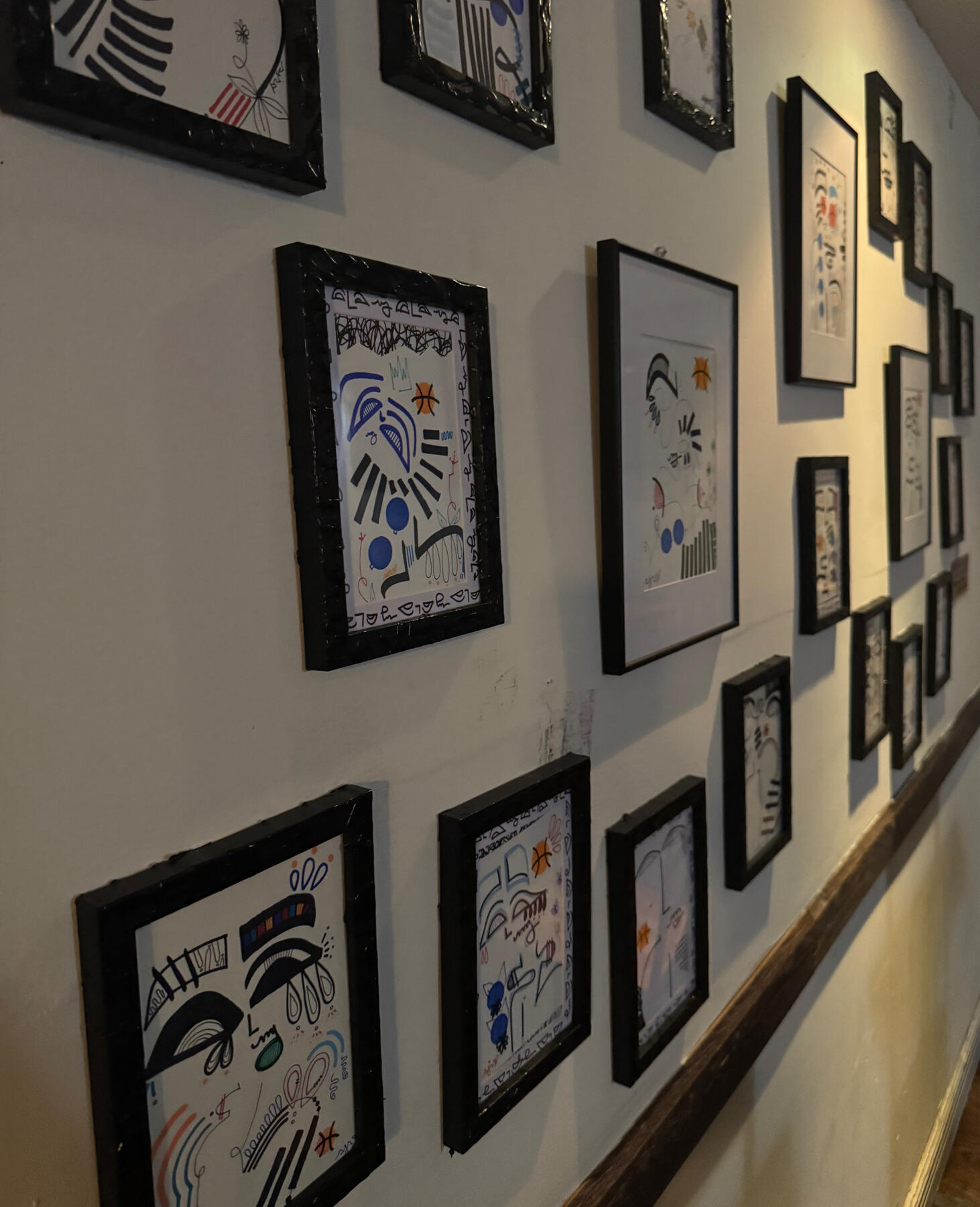 Installation view of shanelle julia rosita’s Homage to New York exhibition with Fanatics, featuring a salon-style wall of framed original abstract marker drawings.